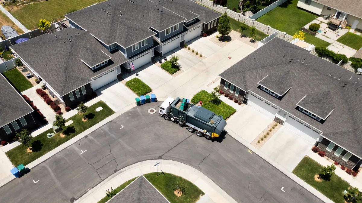 Aerial view of a collection truck picking up waste or recyclables in a residential area