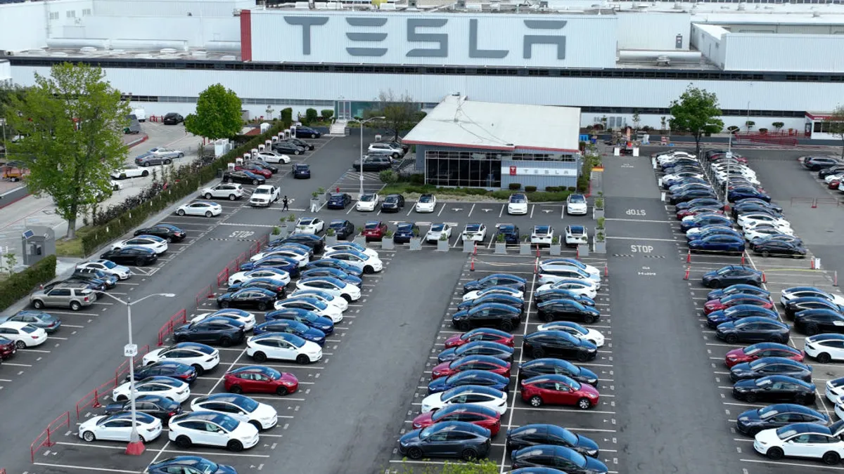 In an aerial view, Tesla cars sit parked in a lot at the Tesla factory on April 20, 2022 in Fremont, California.