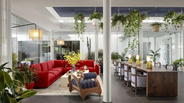 A lounge area includes a red sofa and a long wooden table.