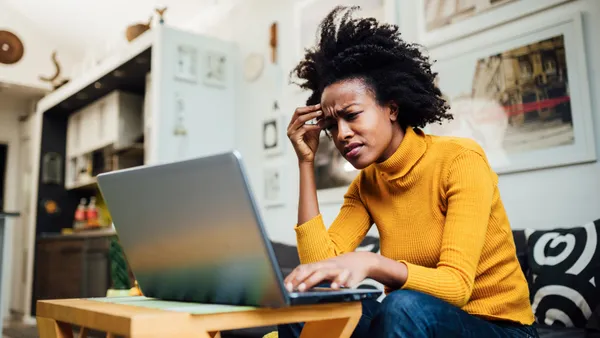 A stressed, frustrated woman uses her laptop.