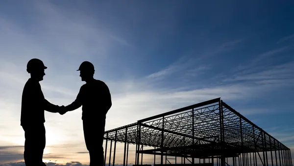 two men shake hands on a construction site