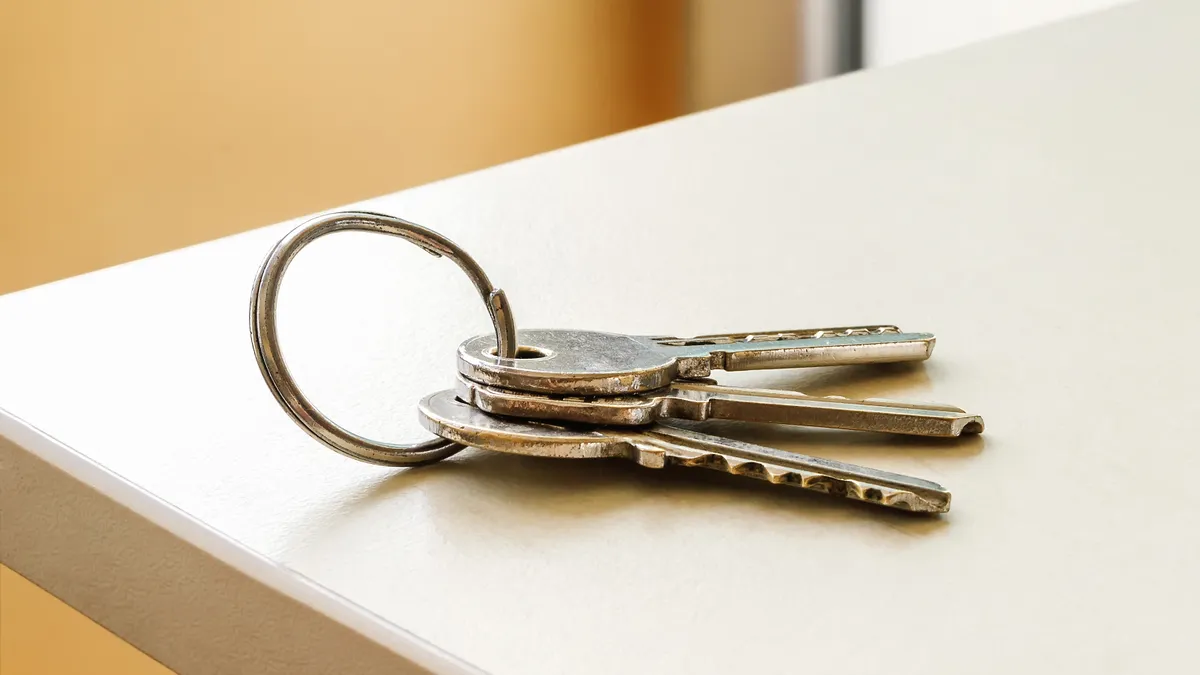 Close up of three metal keys on a keyring sitting on a white table