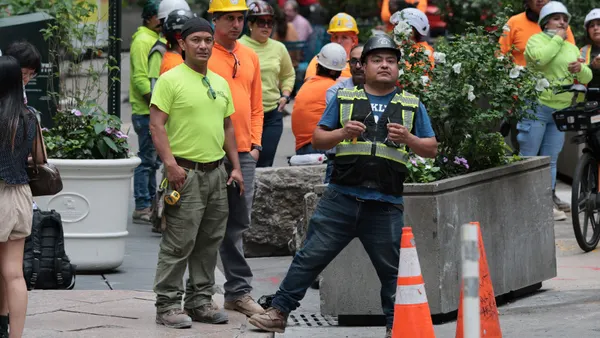 Construction workers gather on the street of a city.