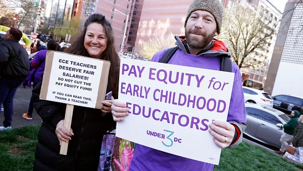 Two people holding signs at a pay equity rally in Washington, D.C.