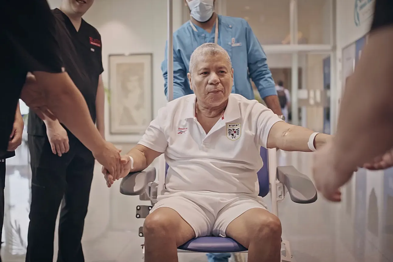 A patient in a wheelchair is surrounded by hospital staff as he prepares to be discharged.