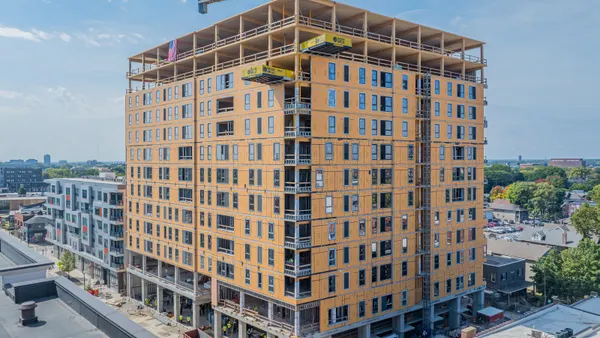 The exterior of a tall building under construction with exposed framing and windows.
