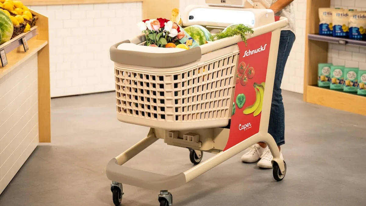 A shopper pushing a Schnucks-branded Caper Cart in a grocery store.