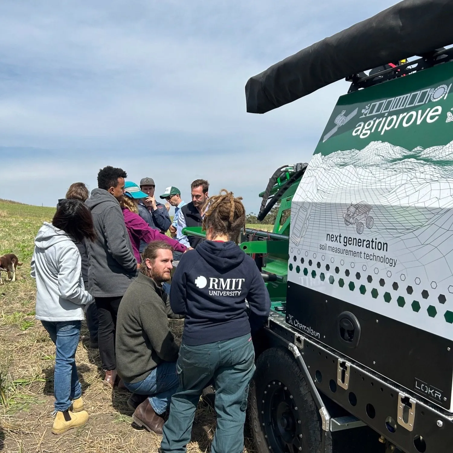 People stand around a soil monitoring robot