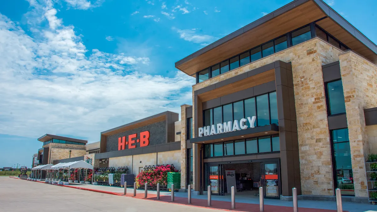 Exterior of supermarket with signs reading "H-E-B" and "pharmacy" on the front.