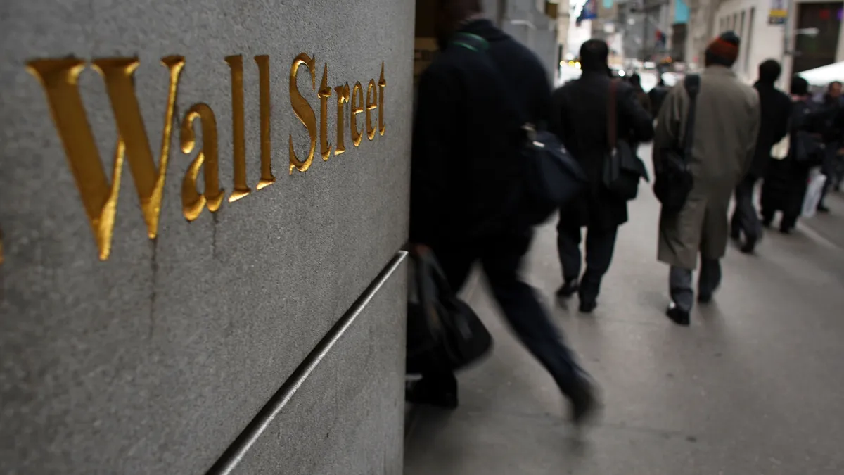 People walk down Wall Street in New York City.