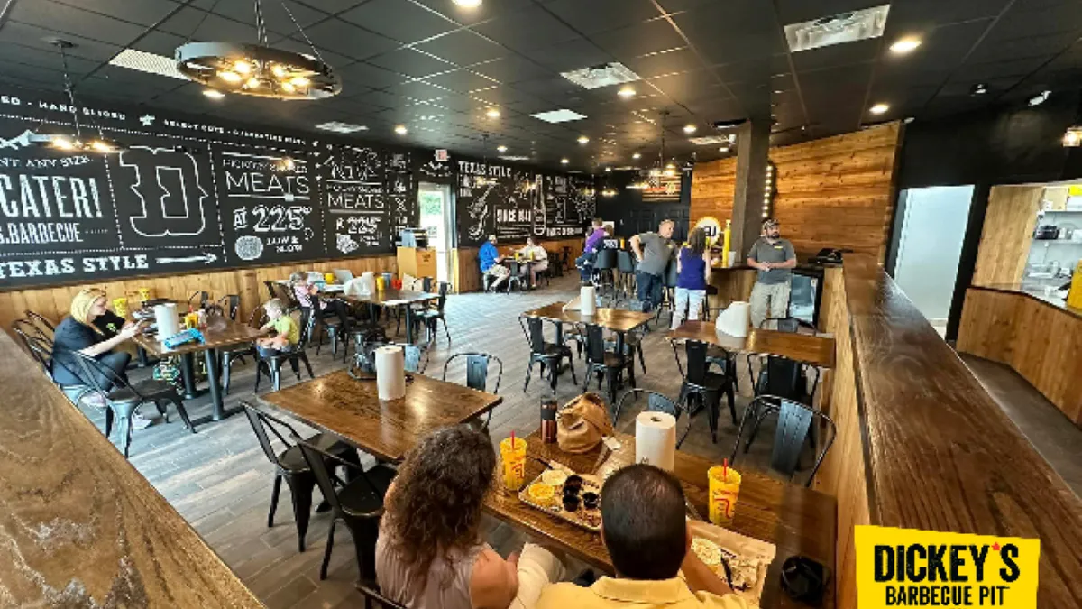 An image of people sitting at tables eating barbecue. The walls say "Dickey's."