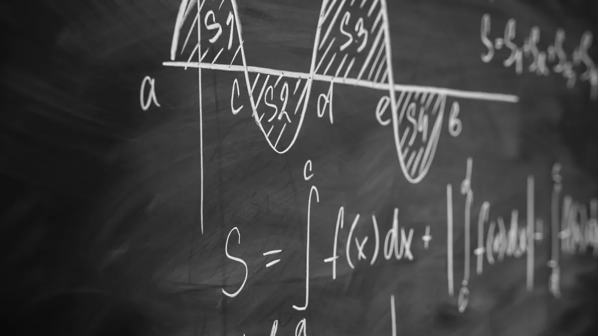 Calculus equations are shown written in white on a blackboard.