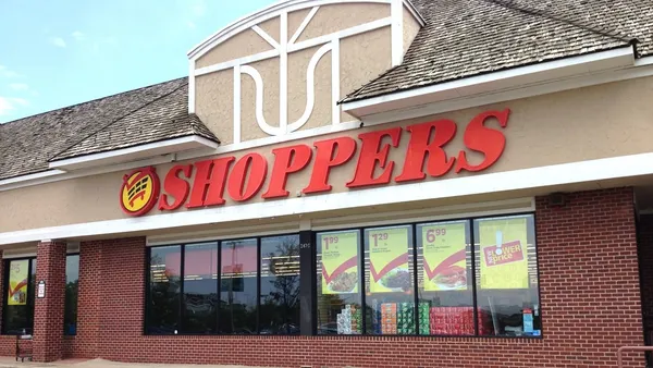 Exterior of supermarket with a dark brick front and a red sign reading "Shoppers."