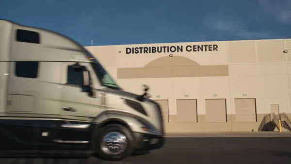 A freight truck driving by a distribution center.