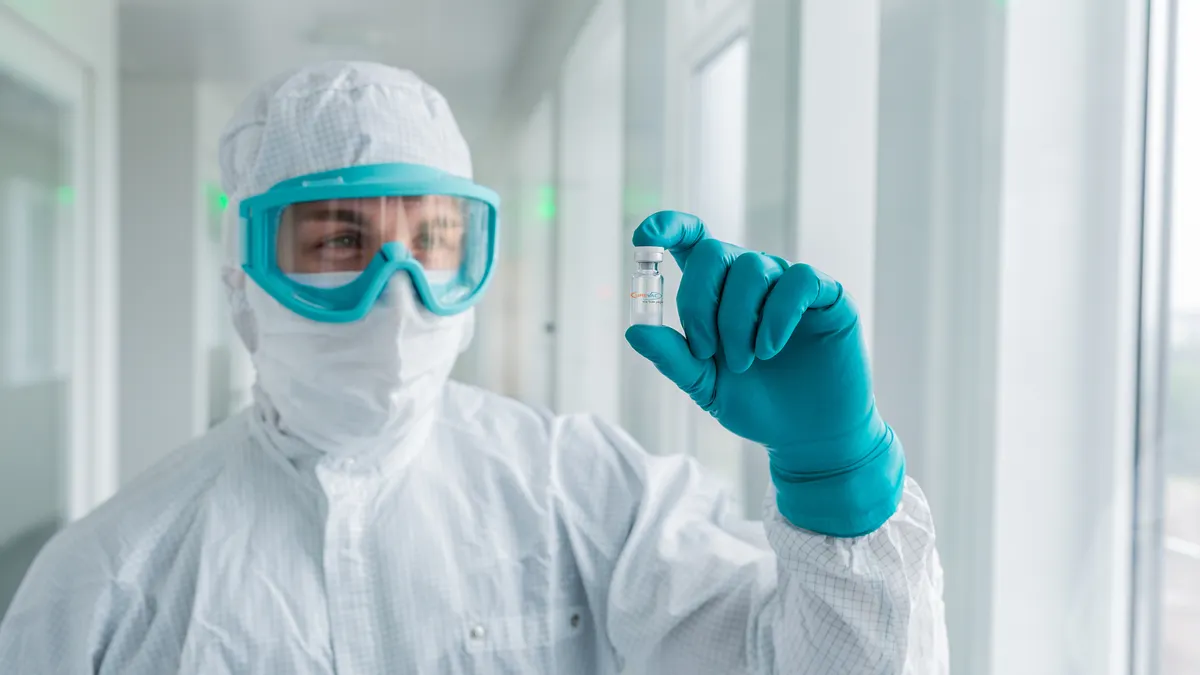 A photograph of a CureVac employee holding up a vial of the company's coronavirus vaccine