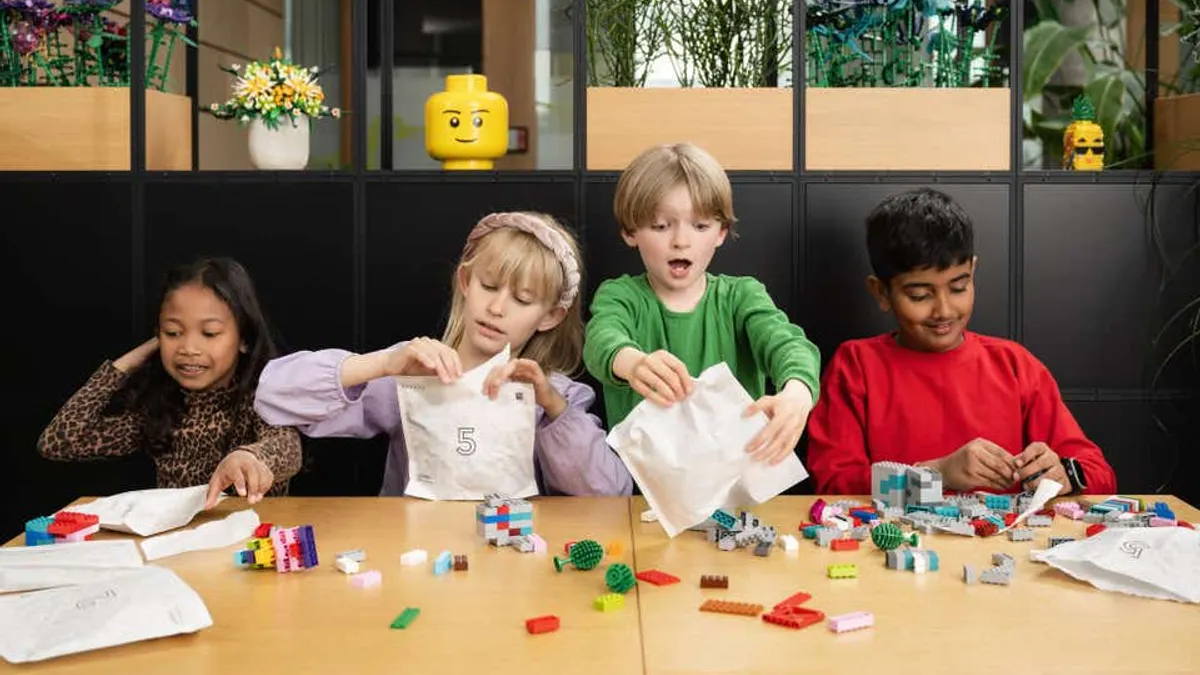 Four children play with Lego bricks and open a paper bag containing the bricks.