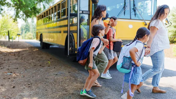 Two moms greet their kids and walk with them home from the school bus stop in their rural neighborhood.