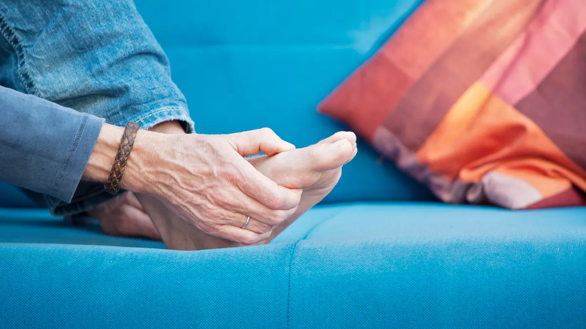 A person cradles their foot at the metatarsophalangeal joints.