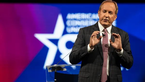 Ken Paxton giving a speech with both of his hands raised in front of his chest