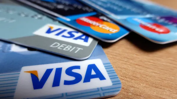 Close-up of several overlapping bank cards on a wooden surface, with Visa and Mastercard logos visible.