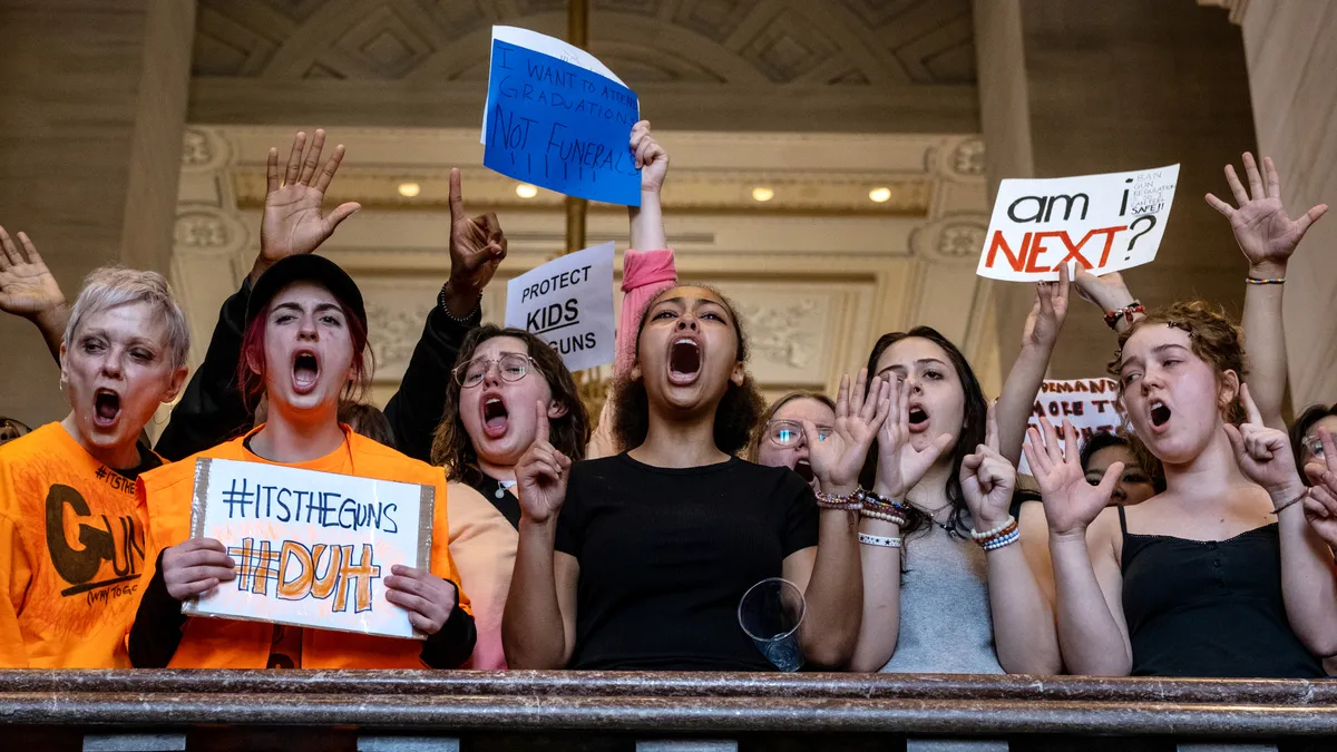 Teenage protestors hold signs and raise their arms