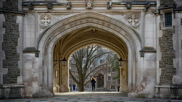 A student walks below a large archway at Princeton University's campus.