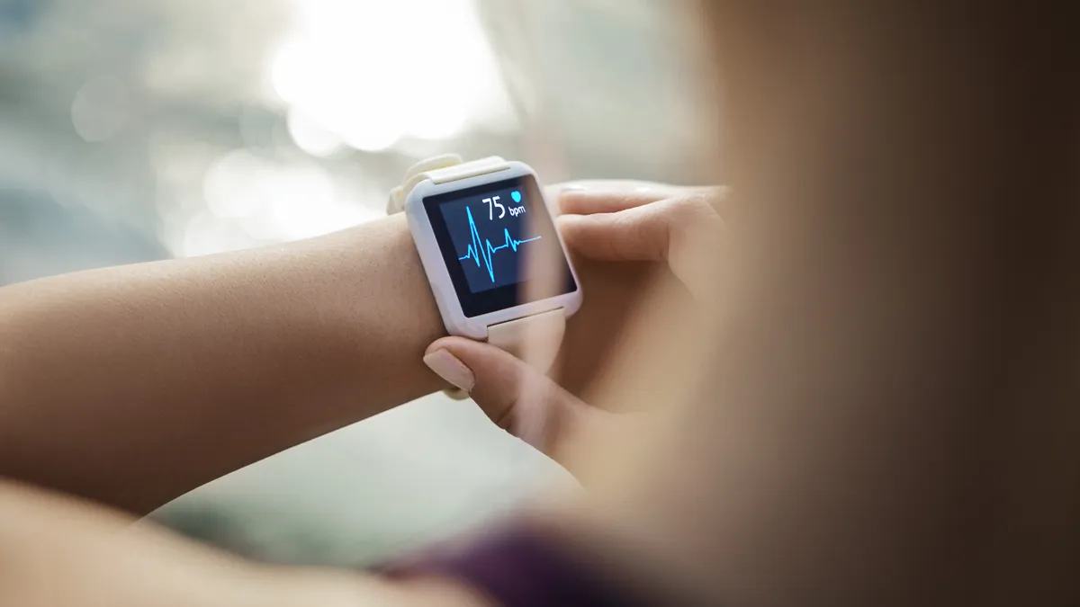 A person looks at their smartwatch, which shows their pulse in blue