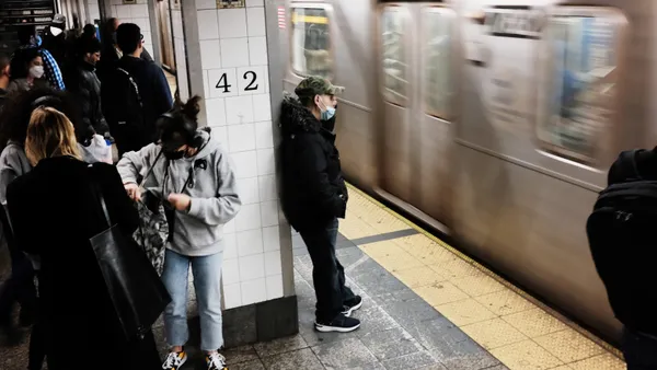 People standing on subway platform with train in motion.