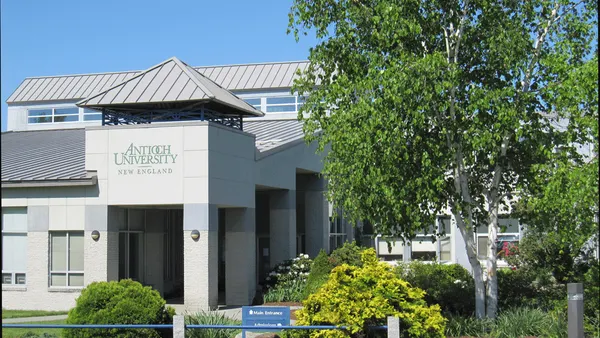 A white modern building with Antioch University banner on turret.