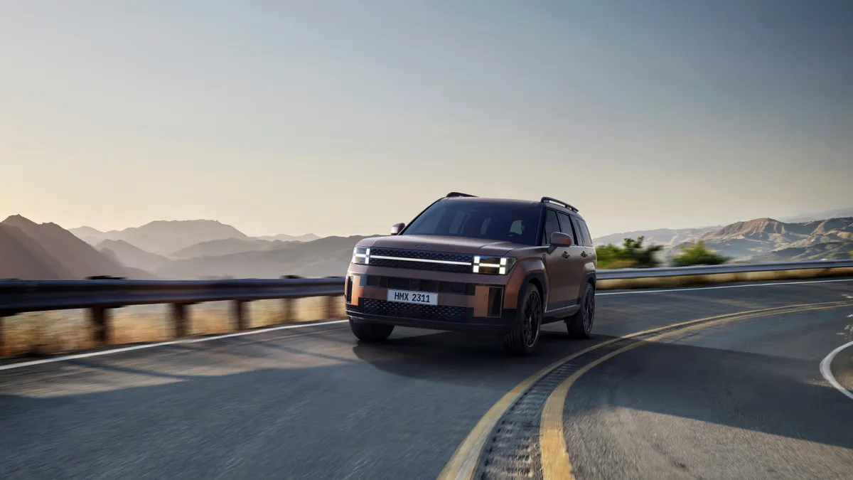 An SUV on the road with hills in the background.