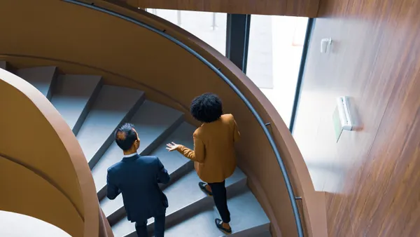 Two people walking up a spiral staircase