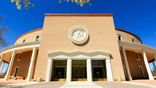 Exterior of the New Mexico state capitol building, which is stucco and prominently features the state seal.