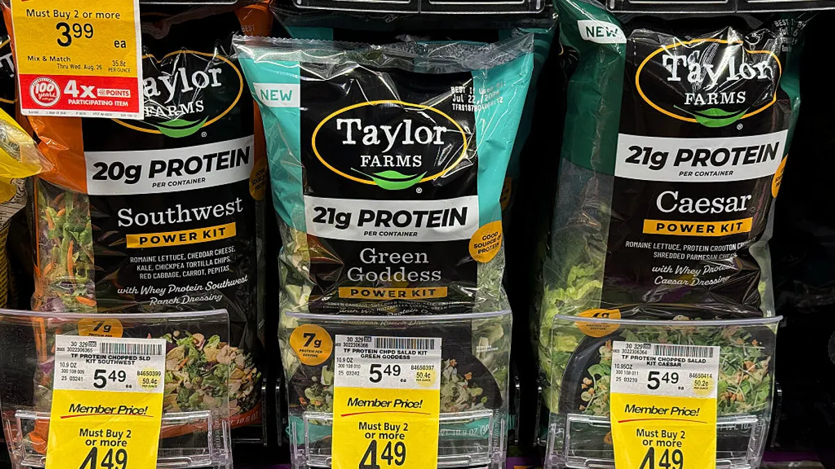 Packages of Taylor Farms salad greens on a store shelf